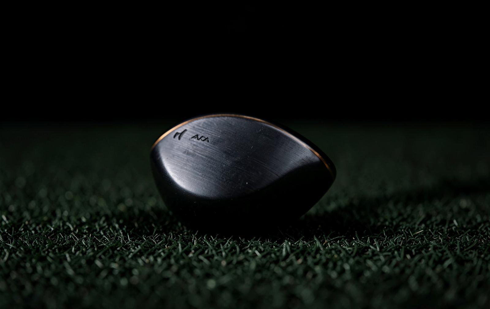 Milled blade putter at address on dark turf
